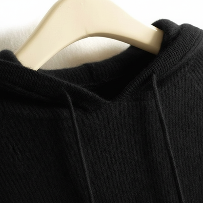 Black cashmere-mink blend hoodie with ribbed trim and drawstring hood on a hanger.