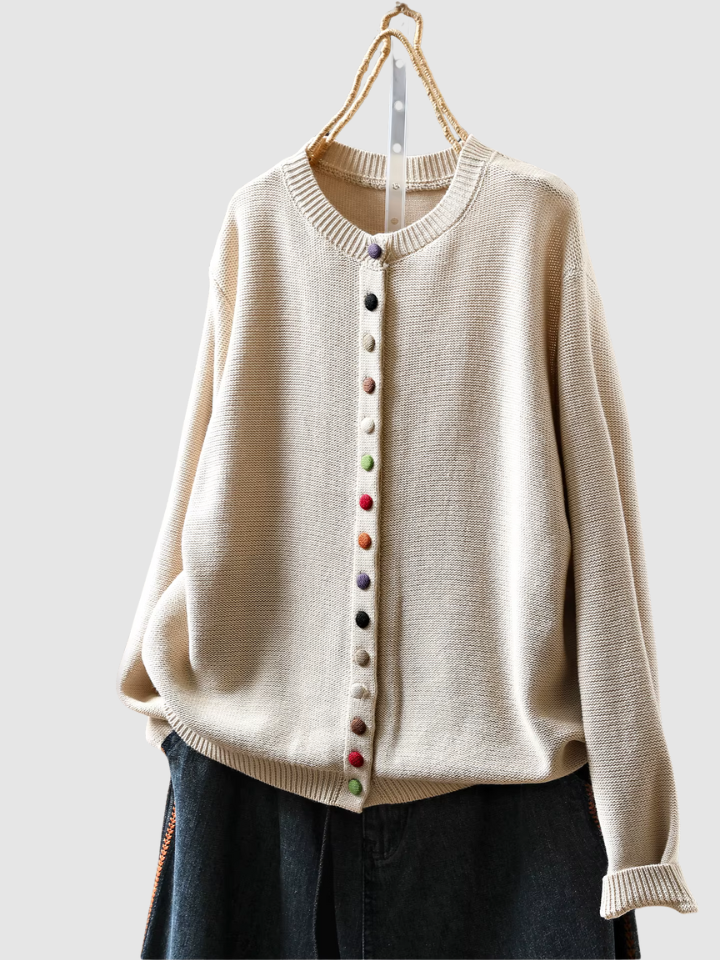 Beige sweater with colorful buttons on a hanger against a white background