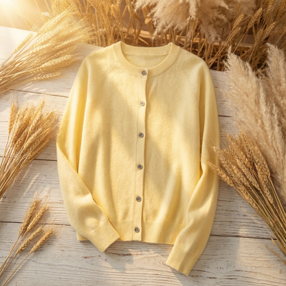 Soft yellow Merino wool cardigan with a classic button-front design and long sleeves, displayed on a rustic wooden surface.